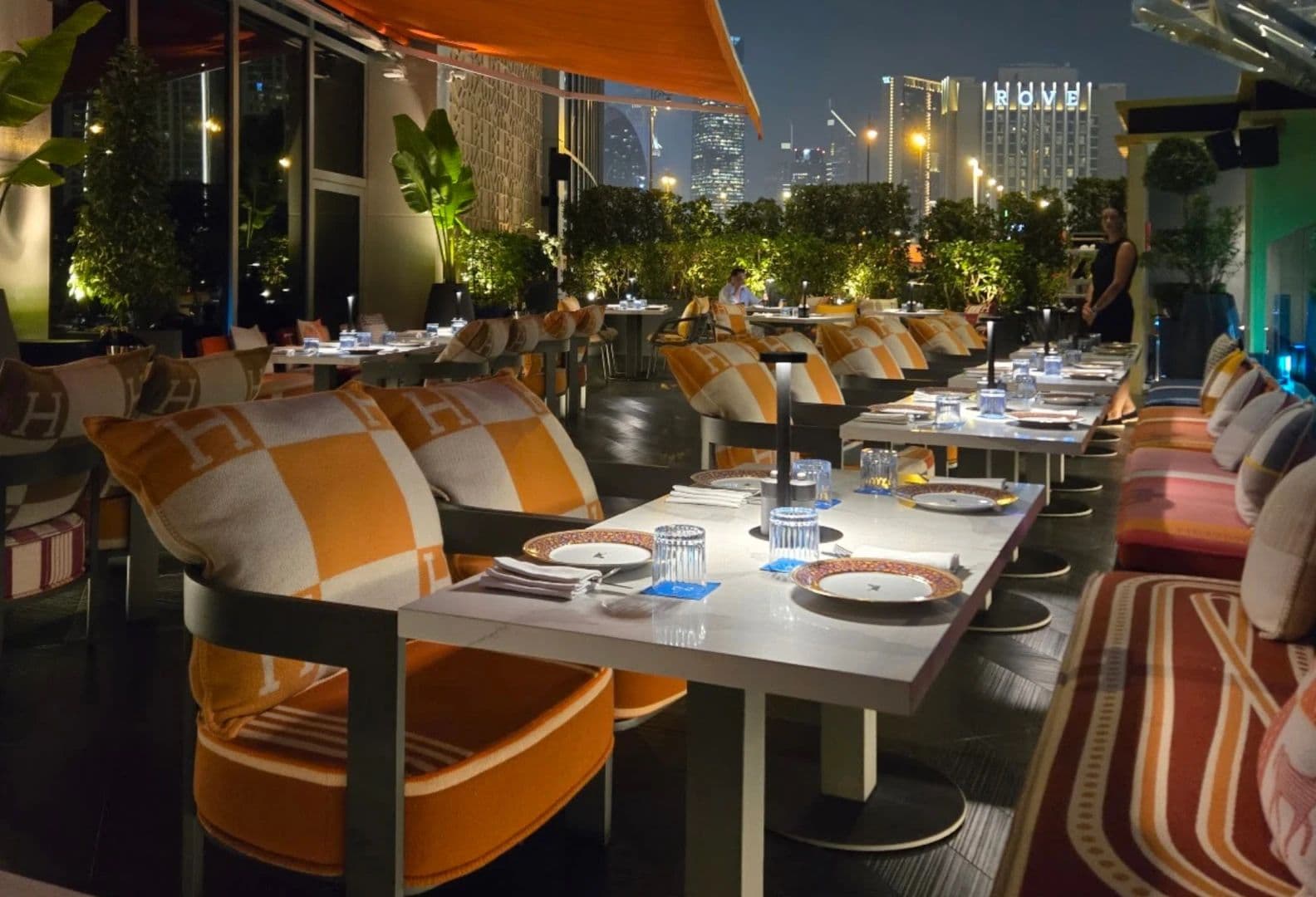 The ZENON terrace at night, a long table set for dinner with the towers of Downtown Dubai beyond