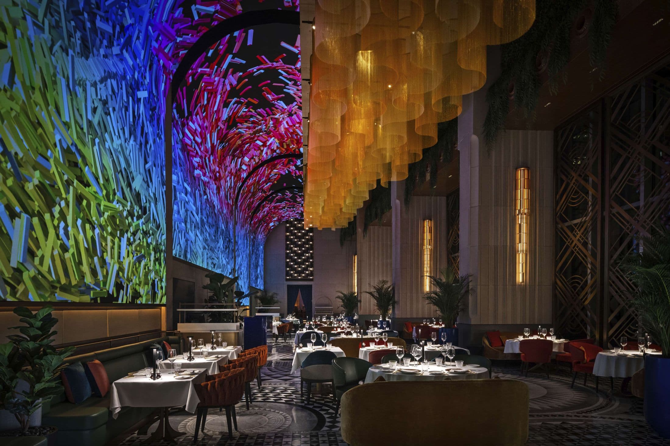 The main dining room at ZENON, Downtown Dubai, with tables laid under immersive LED arches and gold-chain chandeliers