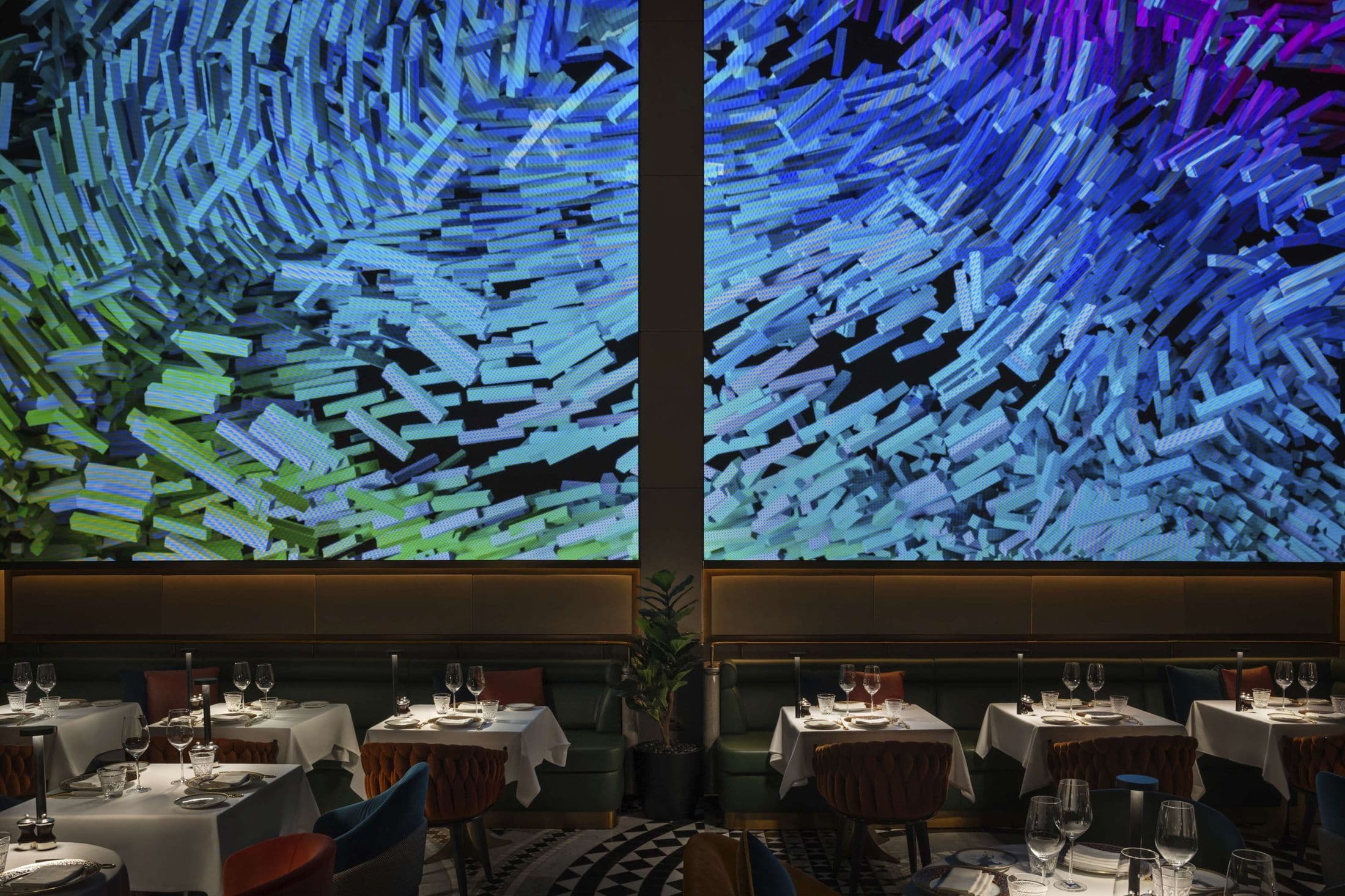 The dining room at ZENON in Dubai, set for dinner beneath two immersive screens